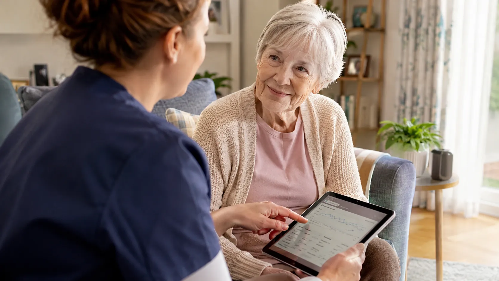 Pflegekraft erklärt einer Seniorin die digitale Pflegeberatung am Tablet